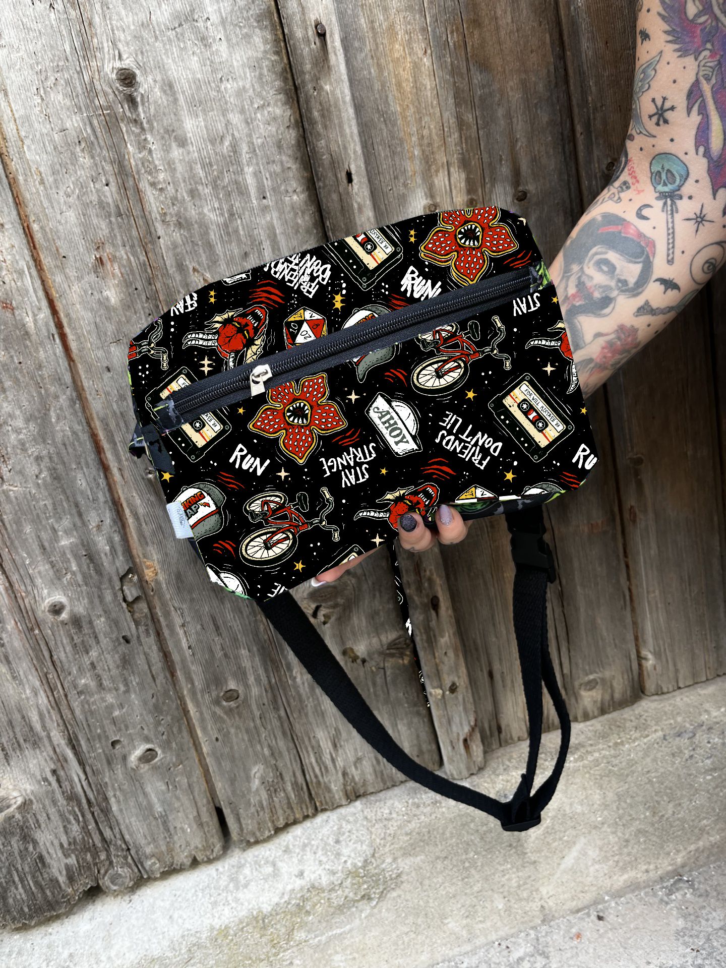 Bolsa de cintura preta com padrão colorido e fecho de correr