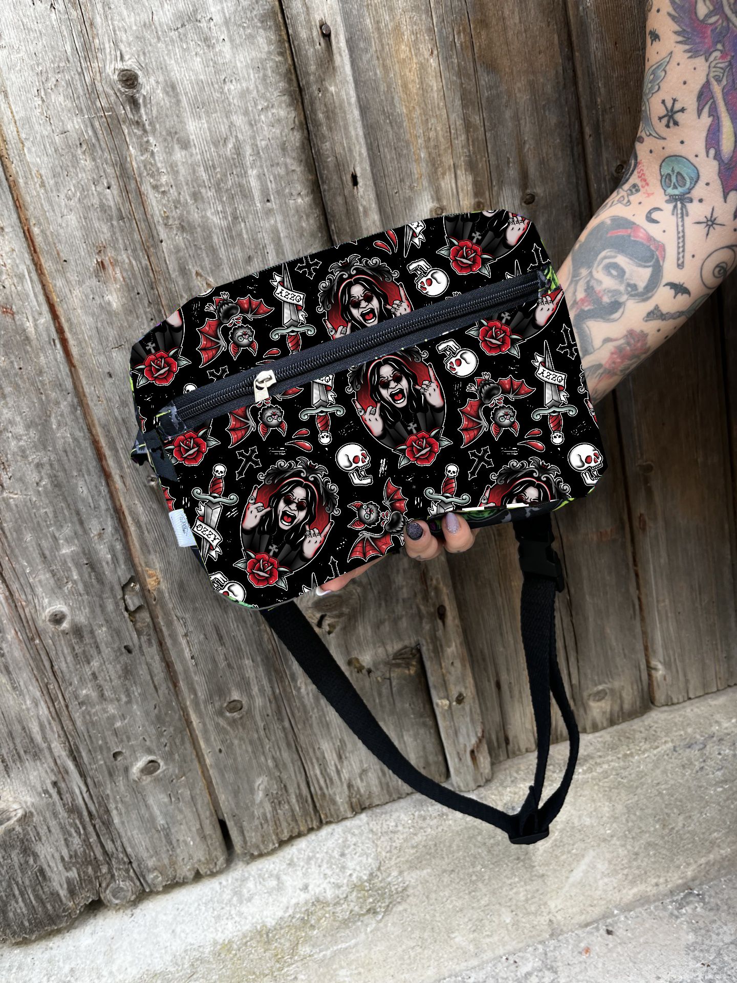 Bolsa pochete preta com padrão de palhaços e rosas, com fechos de correr azuis e alça preta