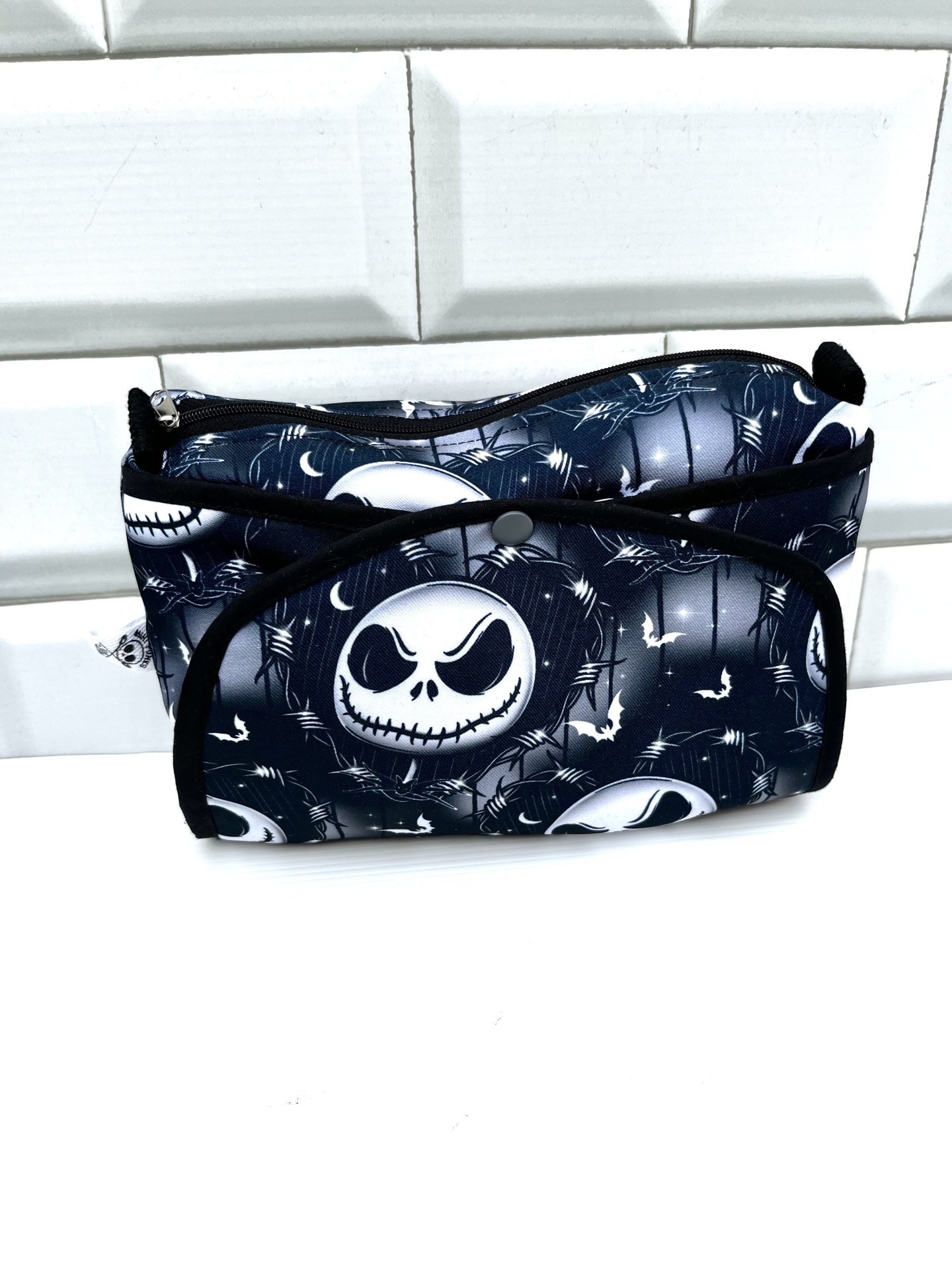 Necessaire preta com padrão de caveiras e aranhas em branco