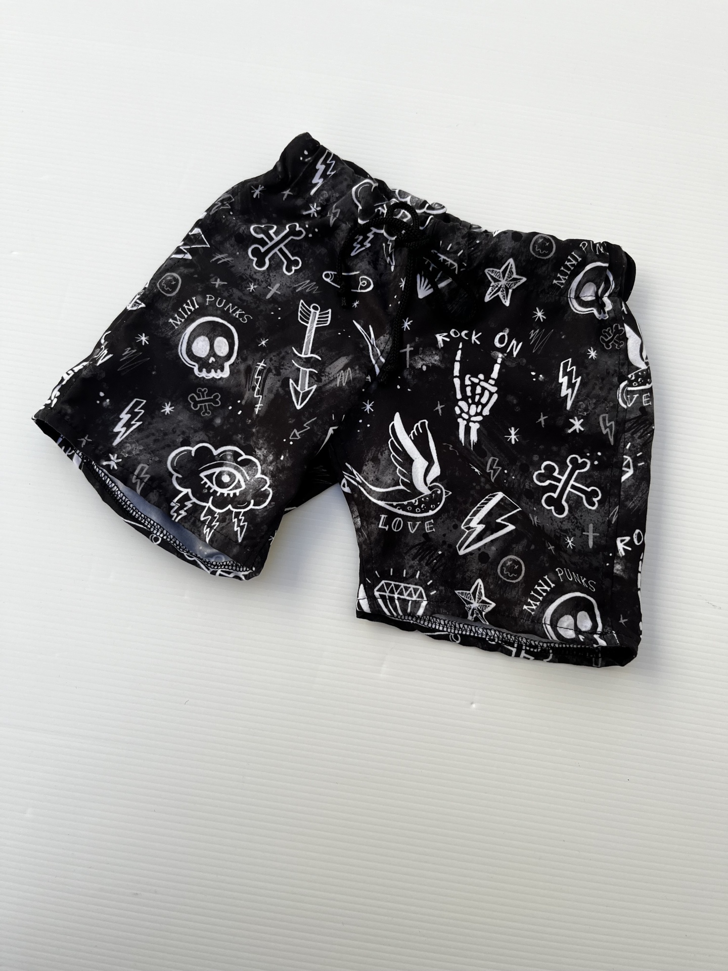 Calções pretos com padrões brancos variados e texto 'MINI PUNKS' e 'LOVE'