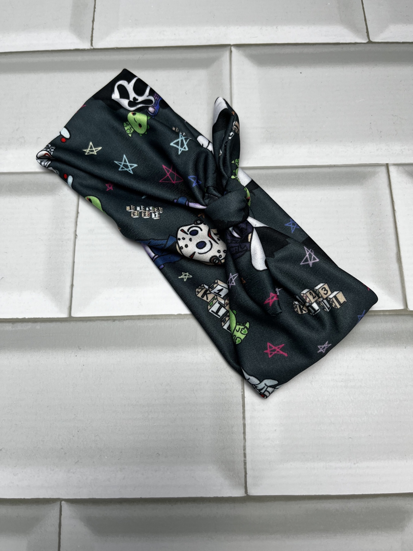 Faixa de cabelo preta com padrão colorido sobre azulejos brancos