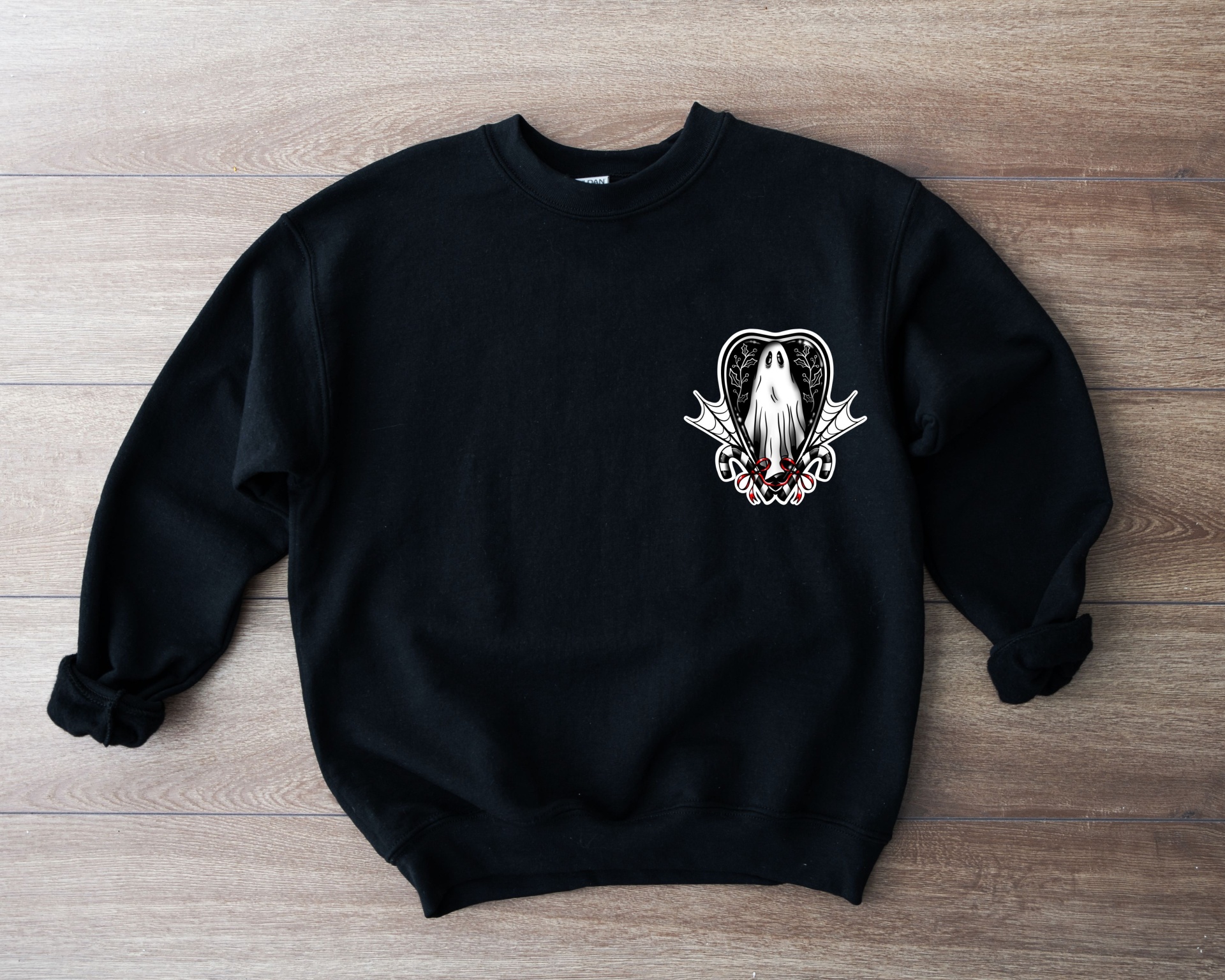 Camisola preta com estampa pequena branca e vermelha no peito sobre fundo de madeira clara