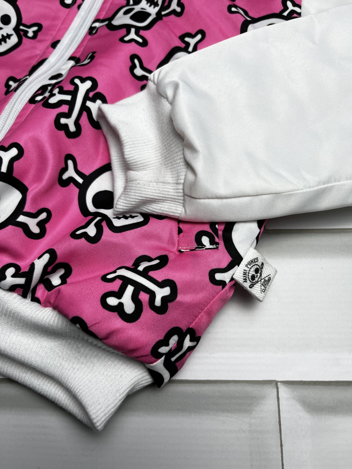 Roupa com padrão caveiras rosa e branco com punhos brancos