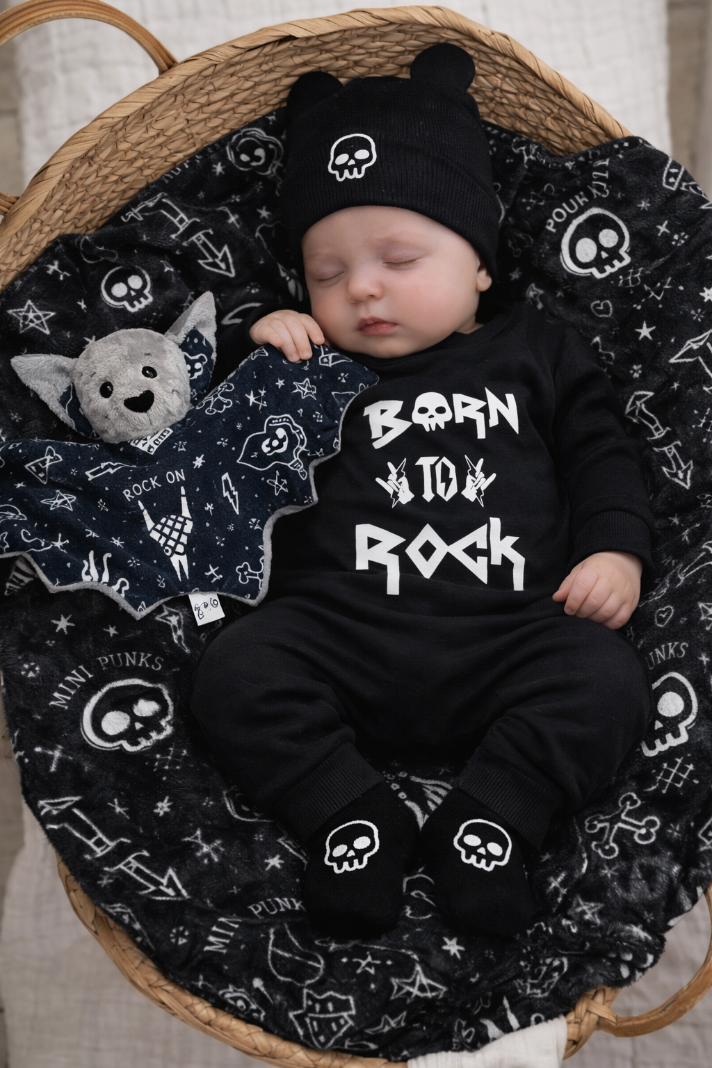 Bebé a dormir vestido com roupa preta com texto branco e detalhes de caveiras