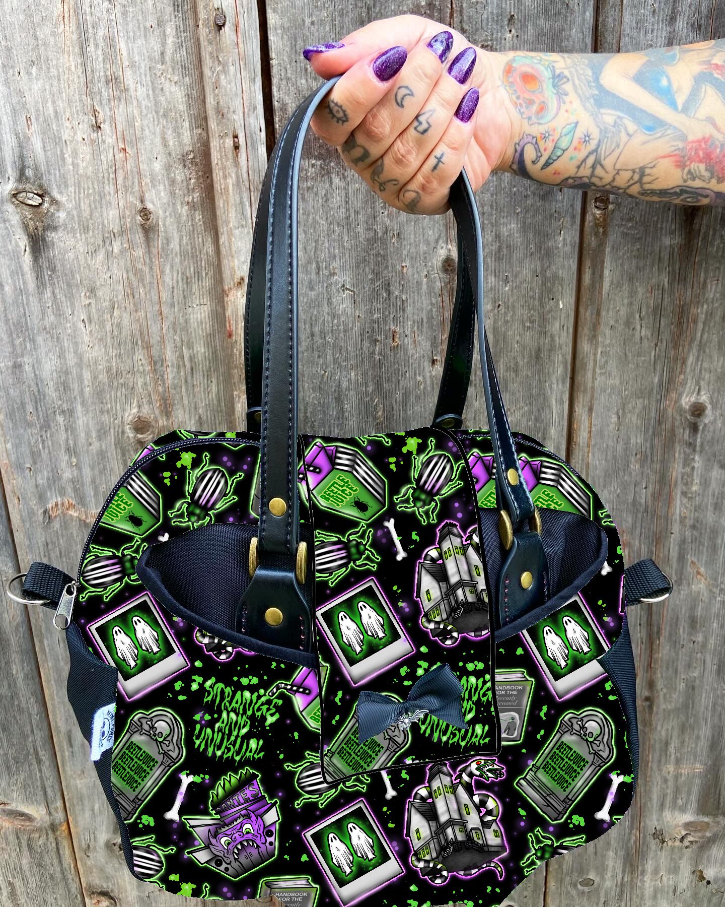 Bolsa preta com estampado colorido de Halloween segurada por mão tatuada.