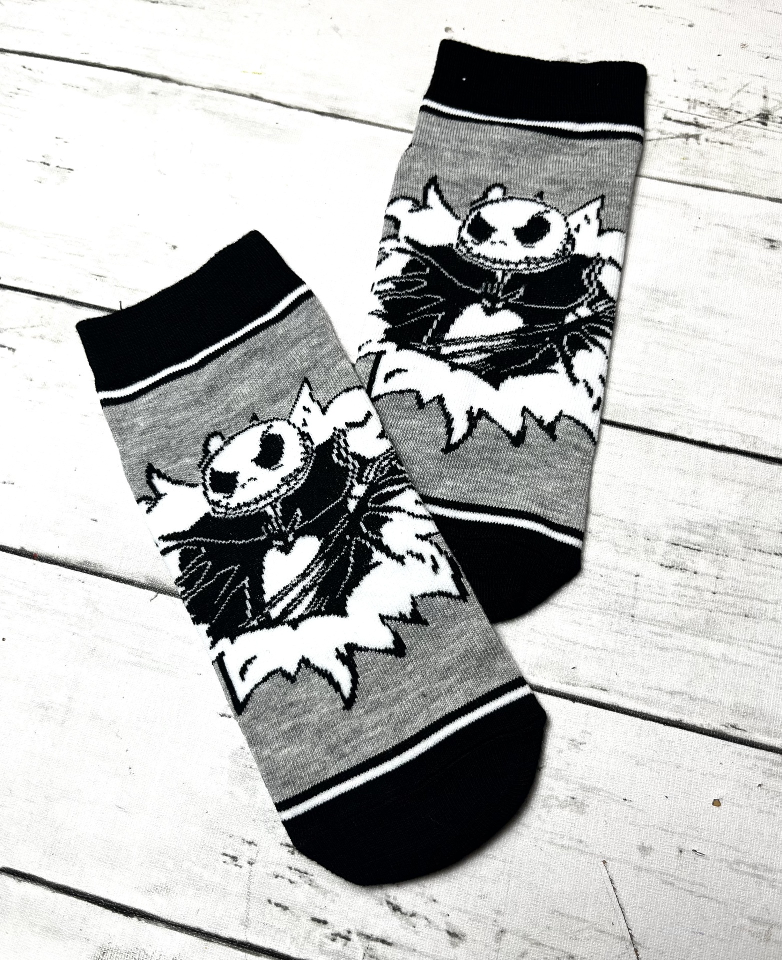 Meias cinzentas com estampa de personagem preto e branco sobre fundo de madeira