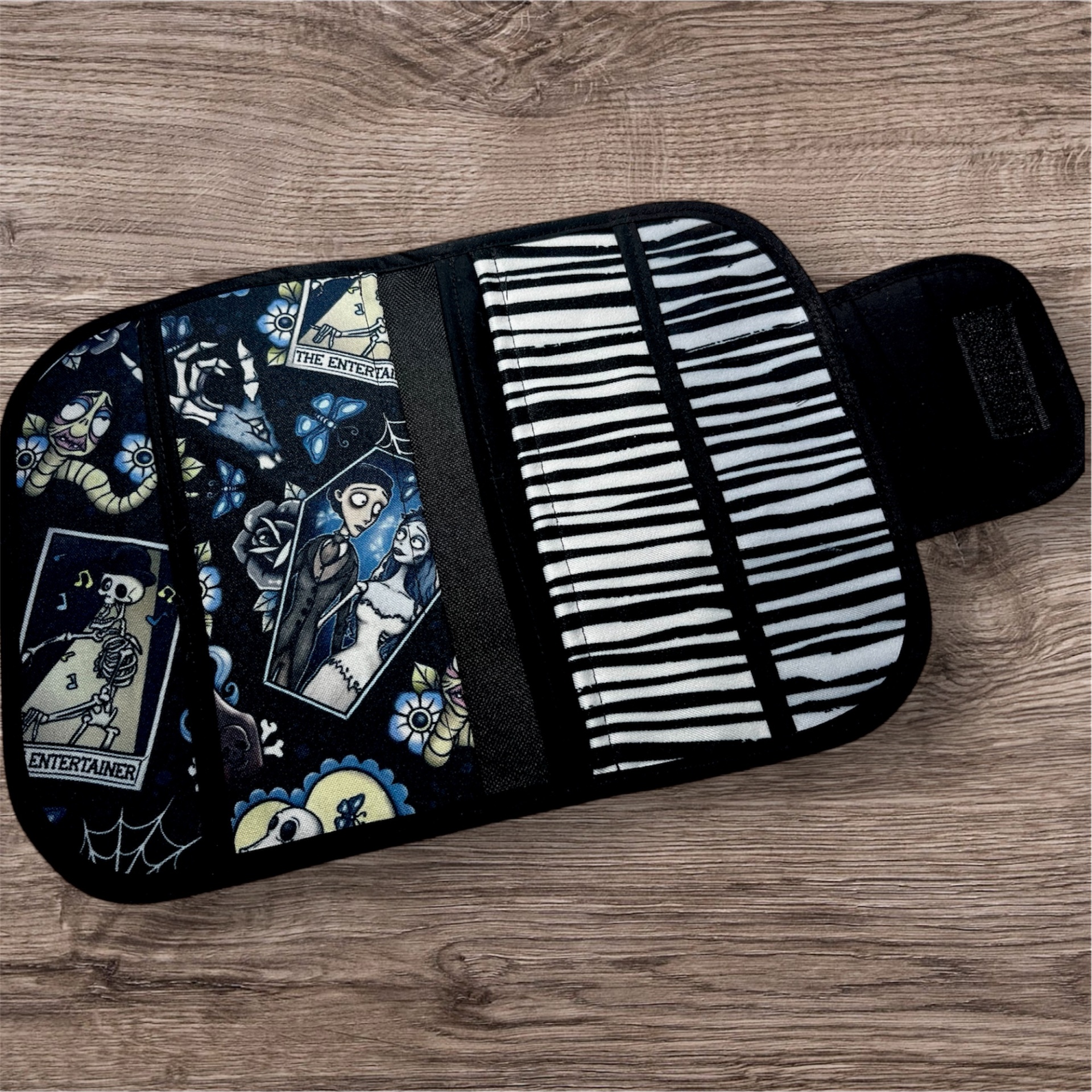 Carteira com padrão de personagens animados e teclas de piano sobre madeira.