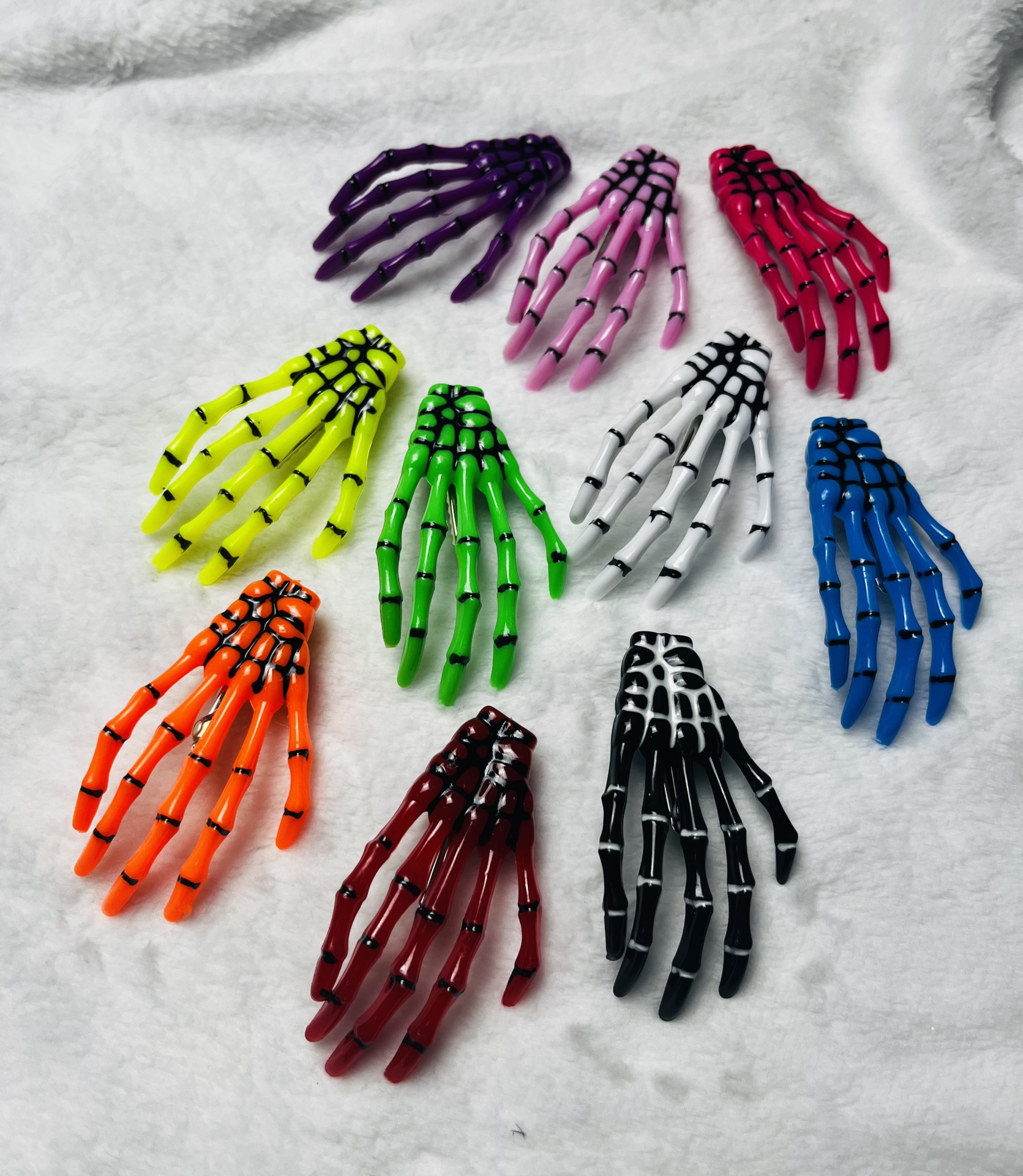 Presilhas de cabelo em forma de mãos esqueléticas coloridas sobre superfície branca
