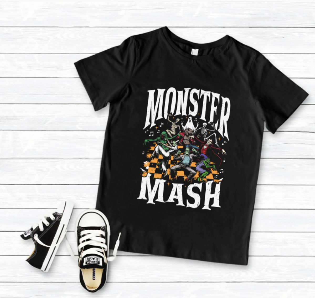 T-shirt preta com estampa MONSTER MASH e sapatilhas pretas com atacadores brancos num fundo de madeira branca
