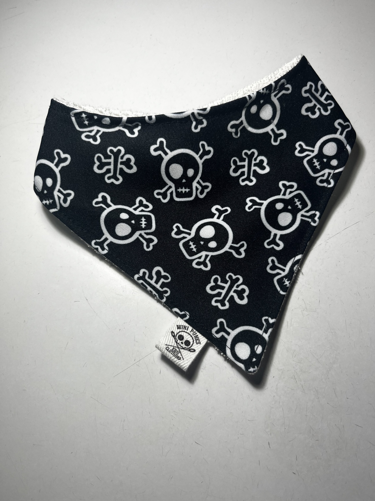 Bandana preta com caveiras brancas e etiqueta MINI PIRATES CLOTHING