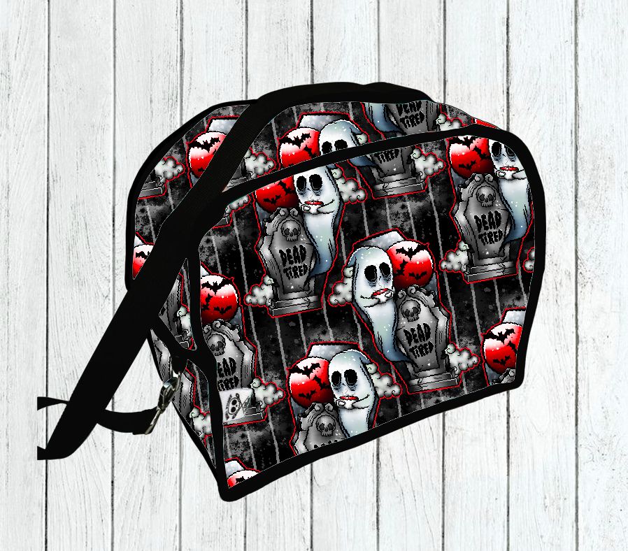 Mala preta com padrão de caveiras, corações e lápides, texto 'DEAD TIED'