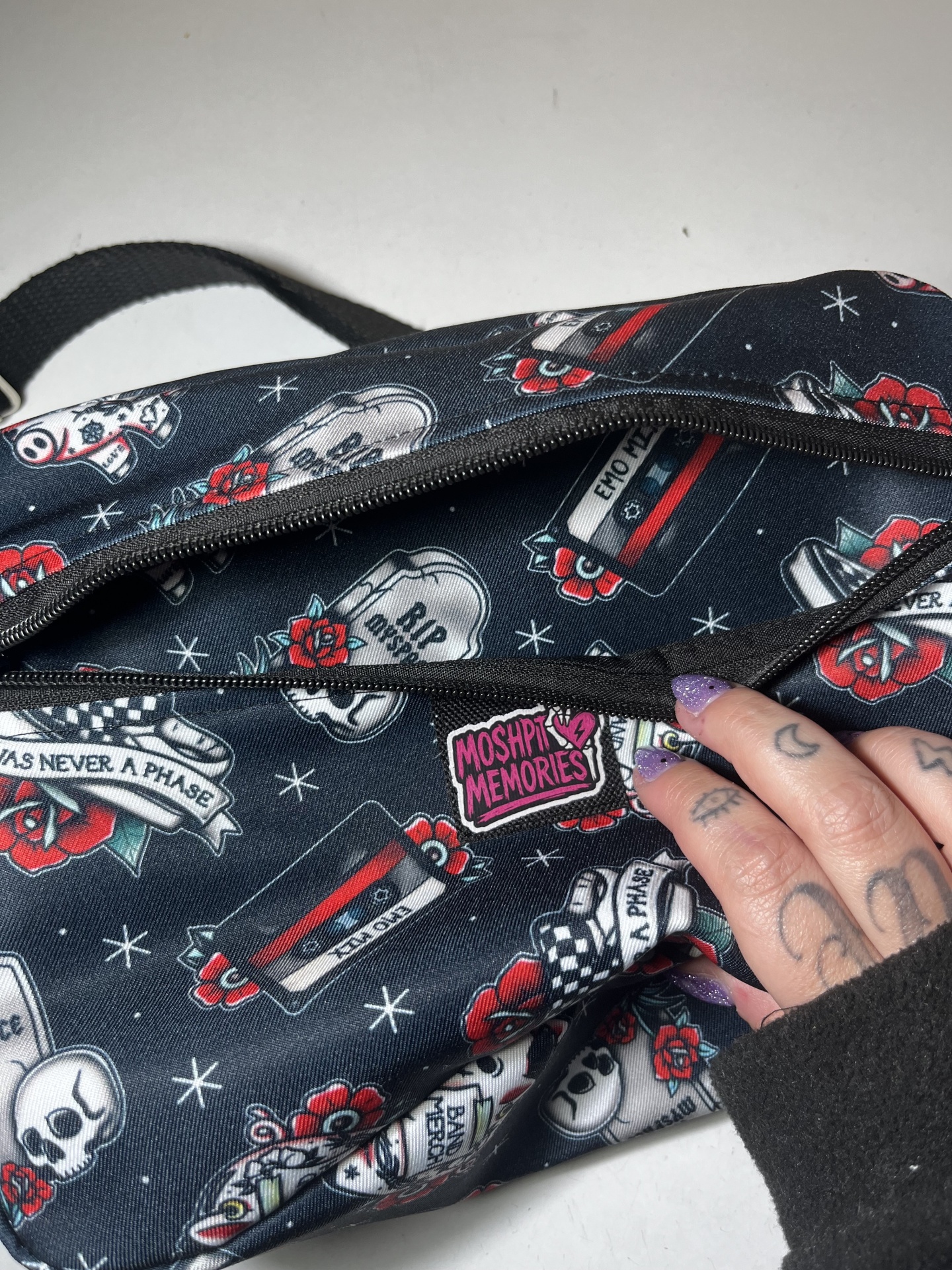 Mala ou bolsa de tecido com padrão estampado de fitas cassete, caveiras, rosas e textos, com fecho de correr preto