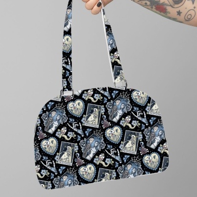 Mala de mão com padrão colorido segurada por uma mão tatuada