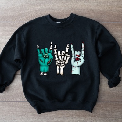 Sweatshirt preta com três mãos desenhadas coloridas na frente, em fundo de madeira clara