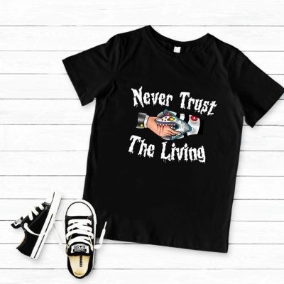 T-shirt preta com estampa colorida e texto com ténis infantis ao lado em fundo de madeira branca