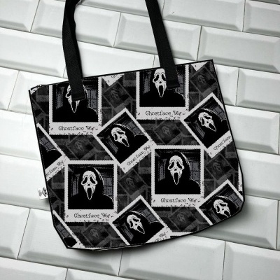 Mala tote preta com estampado de máscaras de 'Scream' em quadros polaroid