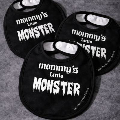 Três babetes pretos com texto branco colocados sobre superfície cinza.