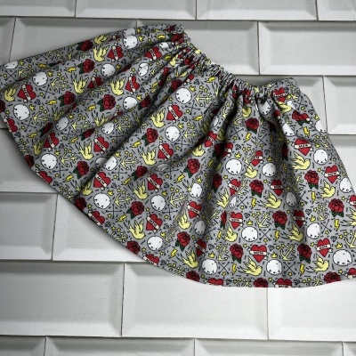 saia cinzenta com padrão colorido e cintura elástica sobre azulejos brancos