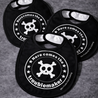 Babetes pretos para bebés com desenho de crânio e texto Here comes the troublemaker