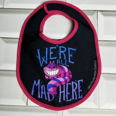 Babete preto com bordadura rosa e ilustração colorida do gato Risonho e texto azul