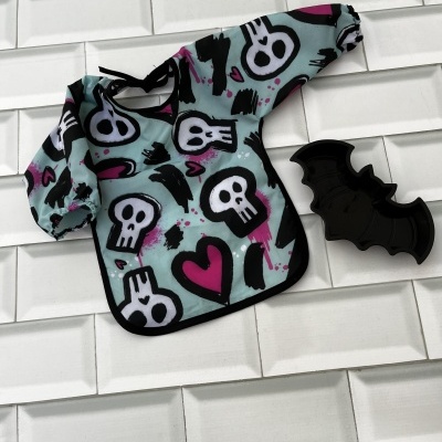 Babete de manga comprida com padrão de caveiras e coração e prato em forma de morcego