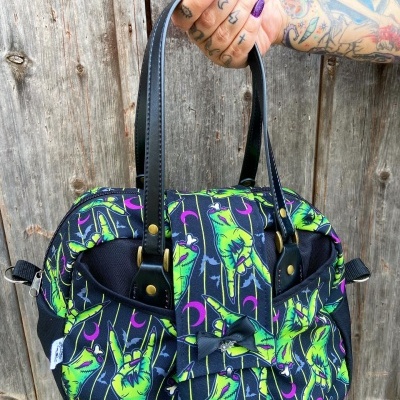 Mala de tecido preta com padrão de mãos verdes, luas lilás e alças pretas