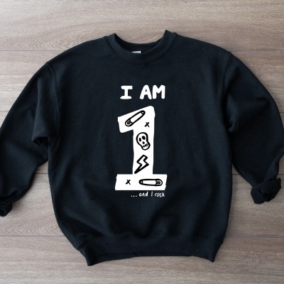 Sweatshirt preta com texto e desenhos brancos sobre fundo de madeira clara