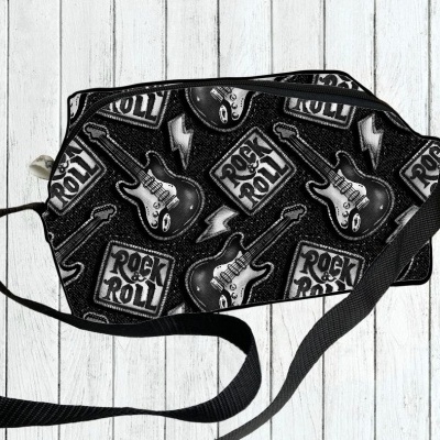 Mala preta com padrão de guitarras e texto 'ROCK & ROLL', alça preta, sobre fundo de madeira branca