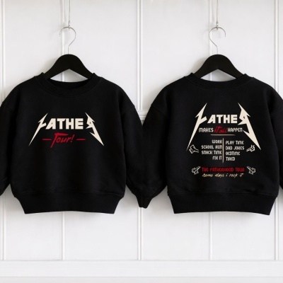 Dois sweatshirts pretos para criança, com estampas brancas e vermelhas, pendurados em cabides pretos contra parede branca.