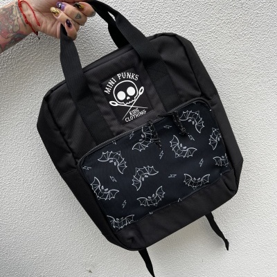 Mochila preta com bolso frontal de padrão morcegos e etiqueta de caveira e texto MINI PUNKS KIDS CLOTHING