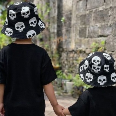 Crianças de costas com chapéus pretos de caveira e t-shirts pretas