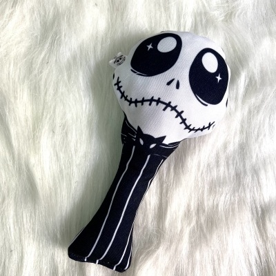 Brinquedo de pelúcia com rosto assustador preto e branco sobre tecido branco