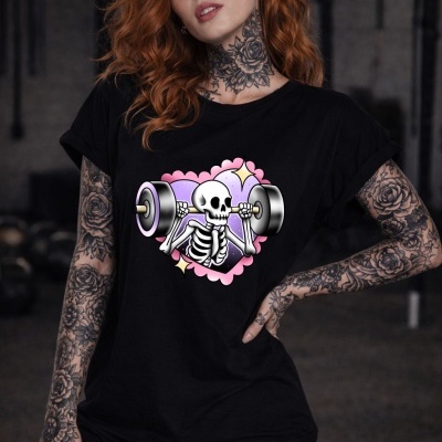 Mulher com t-shirt preta de esqueleto a levantar halteres, tatuagens florais no pescoço e braços.