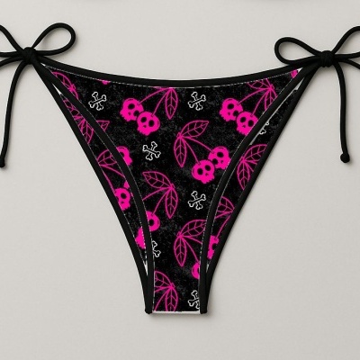 Cueca de banho tanga preta com padrão de caveiras rosas e ossos brancos, com laços pretos nas laterais.