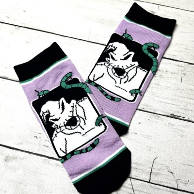 Meias lilás com ponteiras e punhos pretos e desenho de rosto branco com cobras verdes.