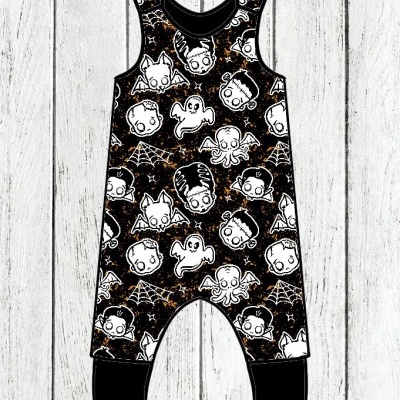 Macacão de criança preto com desenhos de Halloween brancos sobre fundo de madeira
