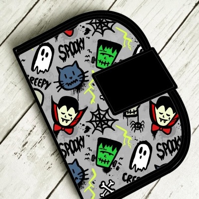 Carteira cinza com padrão Halloween e elementos em preto e vermelho sobre fundo de madeira