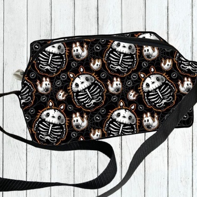 Mala tiracolo preta com padrão de esqueletos e laranja