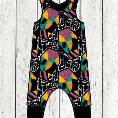 Macacão infantil colorido com padrão geométrico sobre fundo de madeira branca