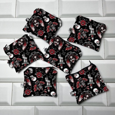 Seis saquinhos pequenos de tecido preto com padrão colorido de caveiras e rosas sobre azulejos brancos