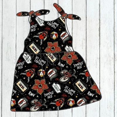 Vestido de criança com padrão colorido e texto em inglês sobre fundo preto