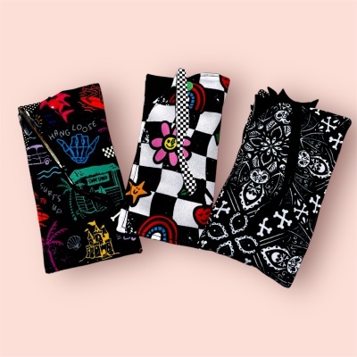 Três peças de roupa dobradas com diferentes padrões coloridos e fundo rosa