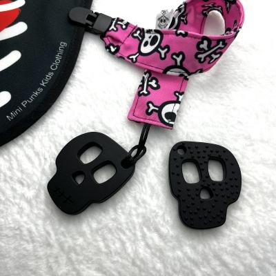 Babete preta com texto e acessório em fita rosa com padrão de caveiras