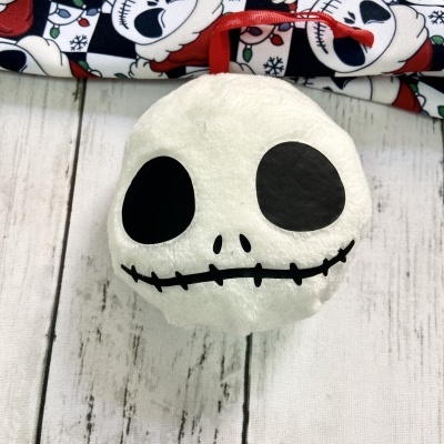 Pelúcia branca de crânio com laço vermelho pendurado sobre madeira branca