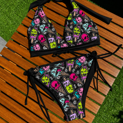 Biquíni preto estampado com gelados e crânios coloridos em banco de madeira