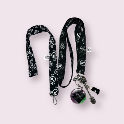 Cordão preto estampado com caveiras e flores, chaveiro com esfera colorida e chaves
