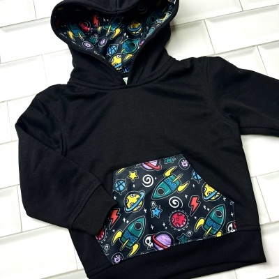 Sweatshirt preta com capuz para criança com bolso e interior do capuz com padrão de foguetes coloridos
