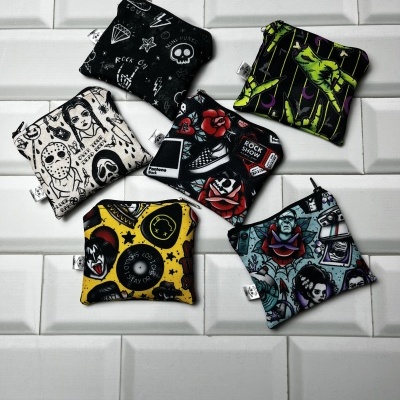 Pequenas bolsas de tecido com designs gráficos coloridos e preto e branco sobre azulejos brancos 3D.