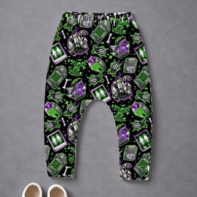 calças para criança com padrão assustador em preto, verde e roxo sobre fundo cinzento