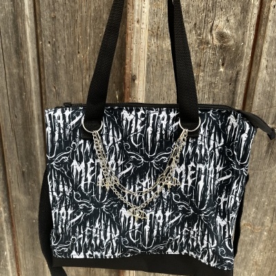 Mala preta e branca com padrão gráfico e corrente prateada